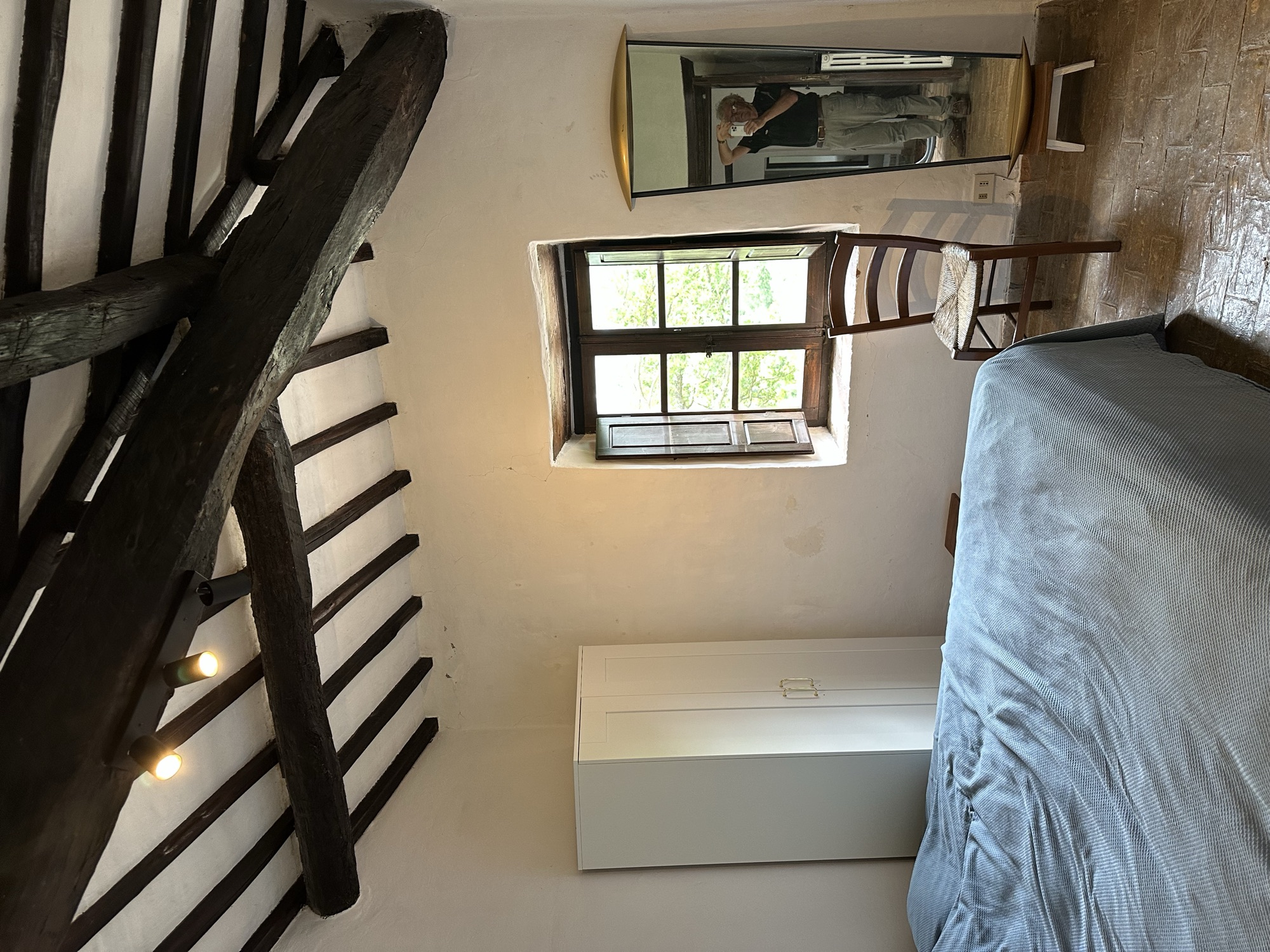 Schlafzimmer mit Doppelbett unter dunklen Deckenbalken