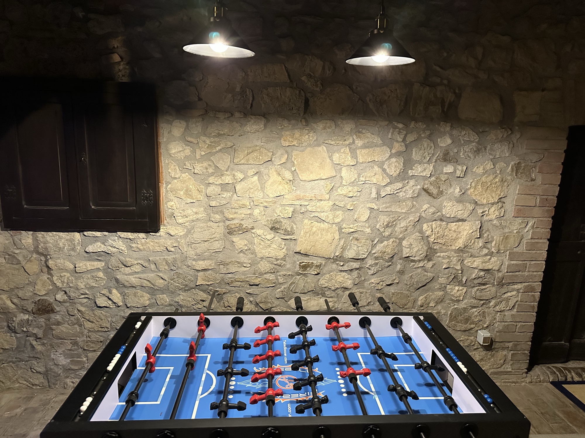 Spielzimmer mit Tischkicker vor einer Natursteinwand